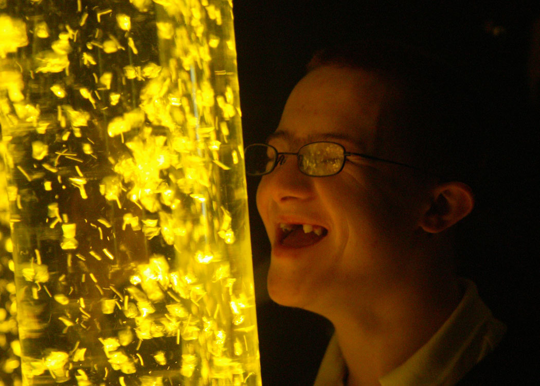 child with down syndrome happily admiring a bubble tube
